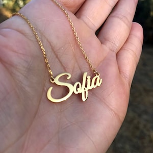 May include: A gold chain necklace with a cursive name pendant that says "Sofia".
