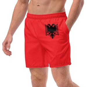 May include: Red swim trunks with a black Albanian flag printed on the left leg.