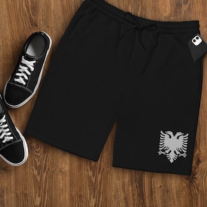 May include: Black sweatpants with a white double-headed eagle design on the right leg. The sweatpants have a drawstring waist and two pockets.