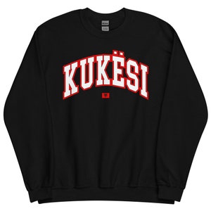 May include: A white ceramic mug with a black handle and the text "But First, Coffee" in a bold, black font. The mug is filled with a dark liquid, likely coffee, and sits on a light-coloured surface.