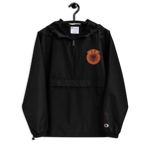 May include: Black Champion windbreaker jacket with a zipper closure and a hood. The jacket has a red and yellow embroidered patch on the left chest with the text "UCK" and an eagle graphic.