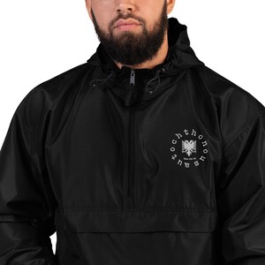 May include: Black hooded windbreaker jacket with a white embroidered circle design featuring a stylized eagle and the text "The Fourth", "Since 1912 BC".