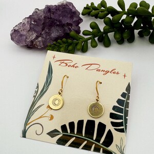 Puede incluir: Pendientes de oro con un diseño de sol y luna en una tarjeta que dice "boho dangles".