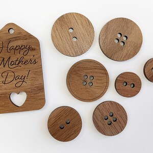 May include: A set of wooden buttons and a wooden tag with the text "Happy Mother's Day!" engraved on it. The buttons are various sizes and have different numbers of holes.