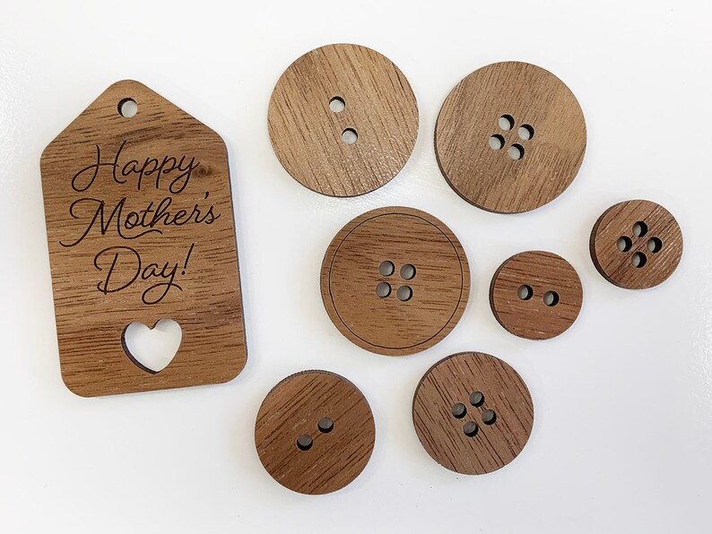 May include: A set of wooden buttons and a wooden tag with the text "Happy Mother's Day!" engraved on it. The buttons are various sizes and have different numbers of holes.