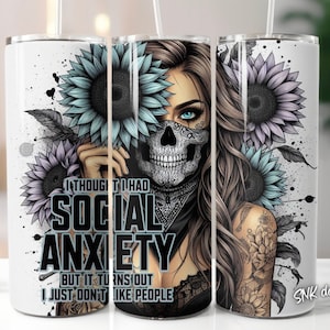 May include: A white tumbler featuring a graphic of a woman with a skull face mask and floral designs. The text on the tumbler reads "I thought I had social anxiety but it turns out I just don't like people".