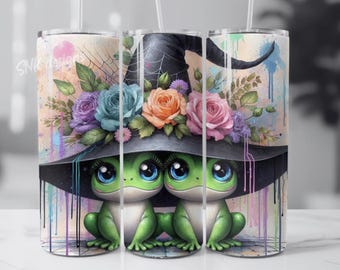 May include: A whimsical tumbler featuring two green frog characters with large blue eyes, wearing a black witch hat adorned with colorful roses. The design includes a spiderweb and watercolor paint drips.