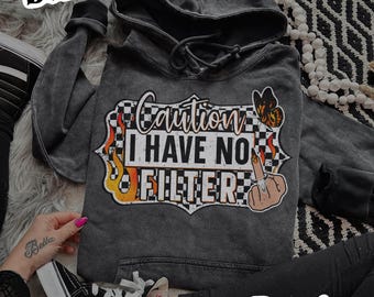 May include: Dark gray hoodie with the text "Caution I Have No Filter" in a graphic design with a butterfly and flames. The hoodie has a drawstring hood and a front pocket. The image also includes black high-top sneakers.