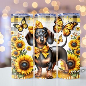 May include: A black and brown dachshund with a yellow bow tie and a butterfly on its back. The dog is surrounded by sunflowers and butterflies on a white background. The image is on a tumbler.