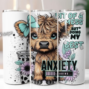 May include: White stainless steel tumbler featuring a cartoon Highland cow wearing a blue bow. The tumbler has the text "Bit of a mess but doing my best" and "Anxiety Loading..." with a progress bar.