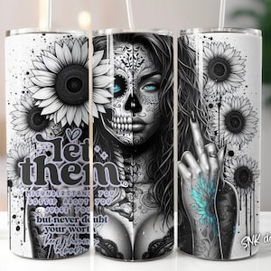 May include: A white stainless steel tumbler featuring a black and white illustration of a woman with a sugar skull face and sunflowers. The text "Let them" is printed in black on the tumbler. The text "Misunderstand you, Gossip about you, Judge you, but never doubt your worth, Keep shining" is printed in black on the tumbler.