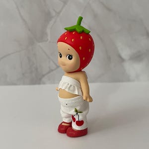 May include: A white ceramic mug with a black handle and the text "But First, Coffee" in a black, bold font. The mug is sitting on a wooden surface. The mug is approximately 4 inches tall.