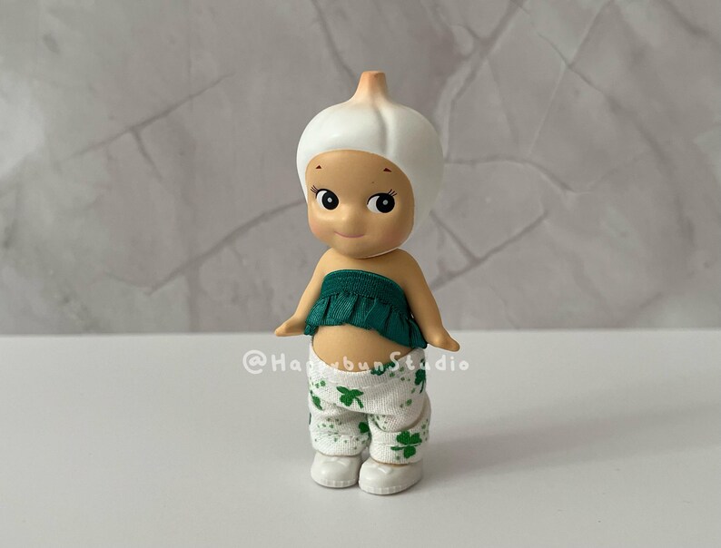 May include: A white ceramic mug with a black handle and the text "But First, Coffee" in a bold, black font. The mug is set against a blurred background, suggesting a cozy setting.