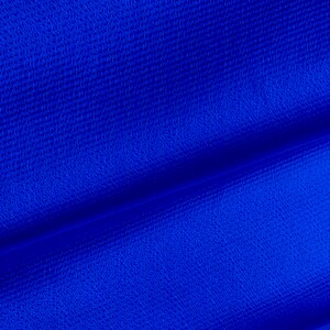 May include: Close-up of a bright blue fabric with a textured surface. The fabric is folded in half, creating a diagonal line.