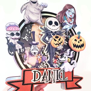 Puede incluir: Una pancarta roja y negra con el nombre "DANIEL" en letras blancas. La pancarta est&aacute; decorada con purpurina y tiene un contorno negro. La pancarta est&aacute; rodeada de personajes de Pesadilla antes de Navidad, incluyendo a Jack Skellington, Sally, Oogie Boogie y Zero.