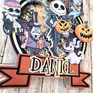 Puede incluir: Un adorno para pastel con personajes de la pel&iacute;cula Pesadilla antes de Navidad. El adorno incluye a Jack Skellington, Sally, Oogie Boogie, Zero y el alcalde. El adorno tambi&eacute;n incluye una pancarta con el nombre "DANIEL".