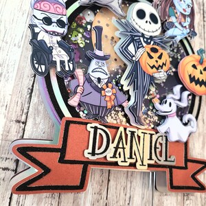 Puede incluir: Un adorno para pastel con personajes de la pel&iacute;cula Pesadilla antes de Navidad. El adorno incluye a Jack Skellington, Sally, Oogie Boogie, Zero y el alcalde. El adorno est&aacute; decorado con brillantina y tiene una pancarta que dice "DANIEL".