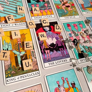 Pode incluir: Um spread de leitura de cartas de tar&ocirc; com as cartas "Oito de Paus", "Oito de Copas", "A Estrela", "Os Amantes", "Rei de Pent&aacute;culos" e "Sete de Copas". As cartas est&atilde;o dispostas em um padr&atilde;o com pe&ccedil;as de letras de madeira que soletram a palavra "futuro".