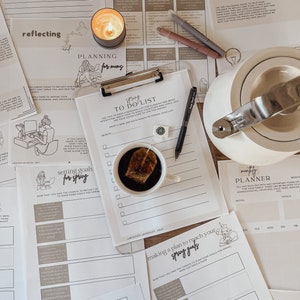 May include: A collection of printable planner pages with a spring theme. The pages include sections for reflecting, planning, setting goals, and making a to-do list. The pages are decorated with hand-drawn illustrations of a woman working on a computer, a teacup, and a watering can.