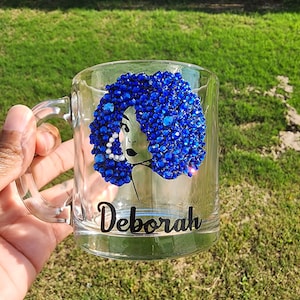 May include: A clear glass mug with a blue rhinestone design of a woman's face and the name "Deborah" printed on the bottom.