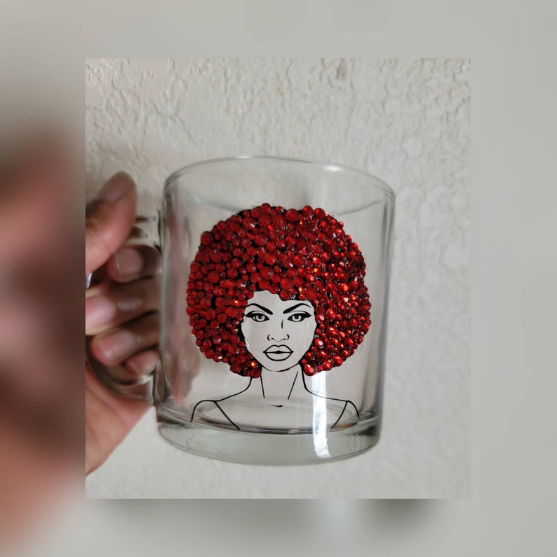 May include: A clear glass mug with a black and white illustration of a woman with a red rhinestone afro.