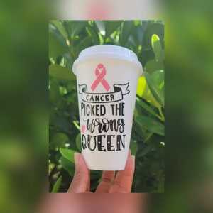 May include: White travel mug with a pink ribbon and the text "Cancer picked the wrong queen".