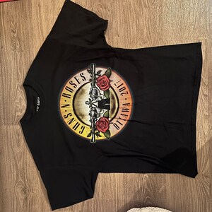 May include: Black t-shirt with a Guns N' Roses logo featuring a gun with roses and the text "Guns N' Roses Ottawa 2017."