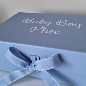 May include: A light blue gift box with a white ribbon and the text "Baby Boy Phee" on the lid.