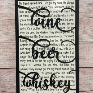 May include: Black and white wood sign with a cut-out design of the word "Whiskey" and a quote about friends, wine, beer, and whiskey. The quote reads, "My friend named Jack. He's got my back. He always seems to know right where I'm at. My friend Jose. He likes to play. Always up for anything I say. Little bit of red, lotta bit of white. Don't matter what it is. I'm gonna drink it down. The wine, the beer, the whiskey. They always get me. My friend named Gin. She's got some friends. I'm talking Brandy, Sherry, and their brother Jim. My friend the Captain. Well, he's Morgan. He likes to anchor down and hang over 'til mornin'. Little bit of red, lotta bit of white. Don't matter what it is. I'm gonna make it all alright. The wine, the beer, the whiskey. Are the only things that fix me. I'm not saying it's a problem. I can stop it if I wanna. But the wine, the beer, the whiskey. They always get me. My friend named Tito. I'm gonna follow him around wherever he go. The wine, the beer, the whiskey. Yeah, they always get me. LITTLE BIG TOWN."