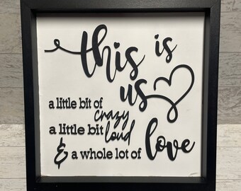 May include: Black and white framed sign with the text "This is us a little bit of crazy a little bit loud & a whole lot of love" with a heart shape.