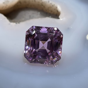 May include: A light purple gemstone with a square emerald cut.