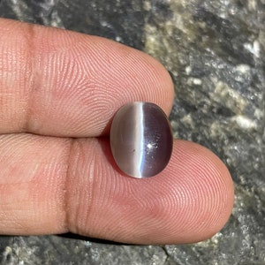 May include: A light purple oval-shaped gemstone with a white iridescent sheen.