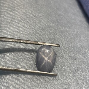 May include: A light blue oval-shaped gemstone with a star-shaped inclusion.
