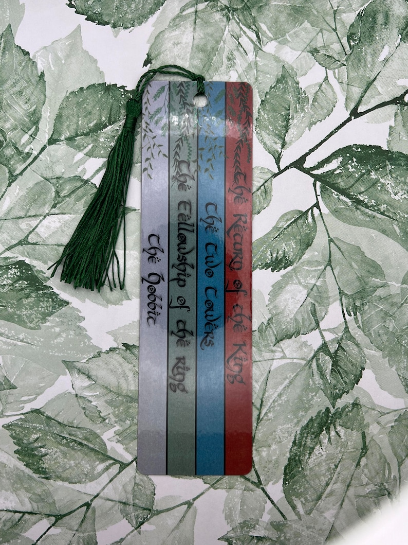 May include: A bookmark with a green tassel, featuring the titles of the Lord of the Rings books: "The Return of the King", "The Two Towers", "The Fellowship of the Ring", and "The Hobbit".