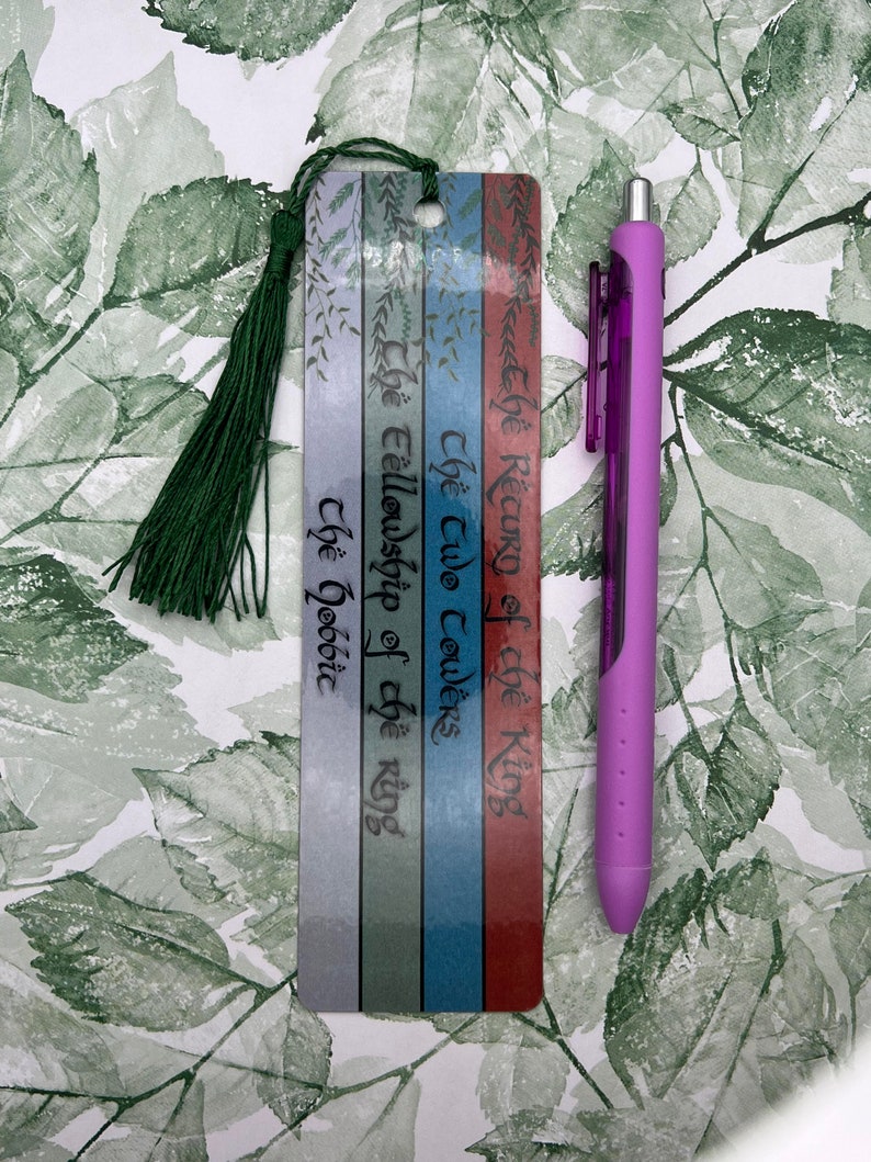 May include: A bookmark with a green tassel, featuring the titles of the Lord of the Rings books: "The Return of the King", "The Two Towers", "The Fellowship of the Ring", and "The Hobbit".