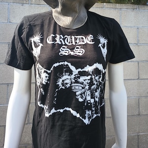 May include: Black t-shirt with a white graphic print of a band called "CRUDE S.S.". The graphic features a band logo and a black and white image of the band members.