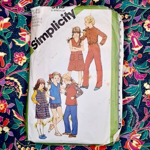May include: Vintage Simplicity sewing pattern number 3718 for girls' dresses and trousers. The pattern includes four different styles, with a variety of colours and patterns. The pattern is printed on white paper with green and black text.