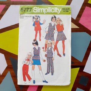 May include: Simplicity sewing pattern number 5777 for children's clothing. The pattern includes four different designs for dresses and trousers with plaid and solid fabrics. The pattern is for size 6, with a 64 cm chest.