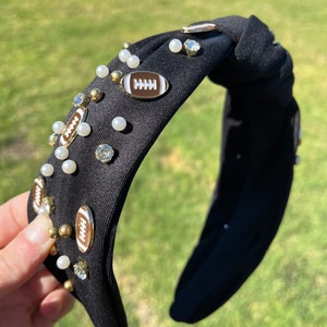 May include: Black knotted headband with white pearls, gold rhinestones, and gold football charms.