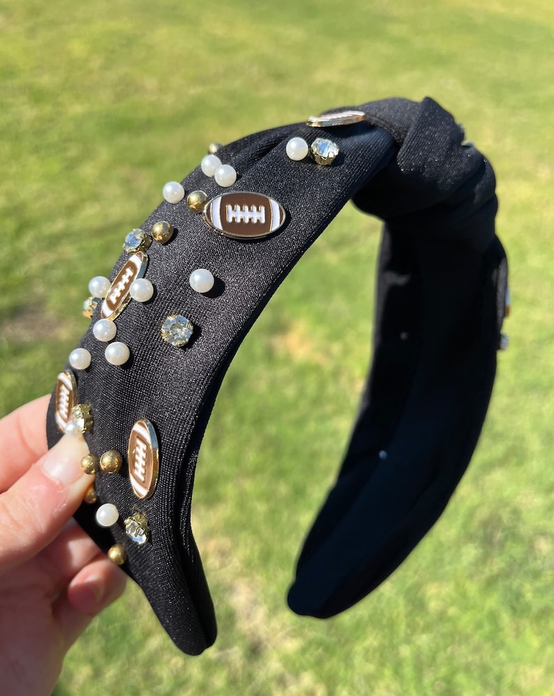 May include: Black knotted headband with white pearls, gold rhinestones, and gold football charms.