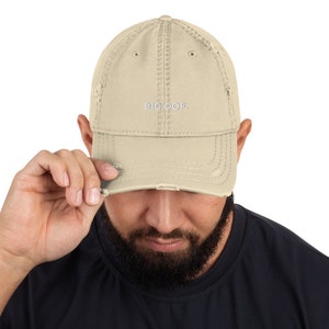 May include: A beige distressed baseball cap with the text "BIG OOF." embroidered in white on the front.