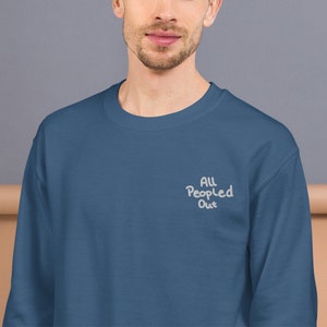 Pode incluir: Uma camisa de frio azul escura com o texto "All People Out" bordado em branco na frente.