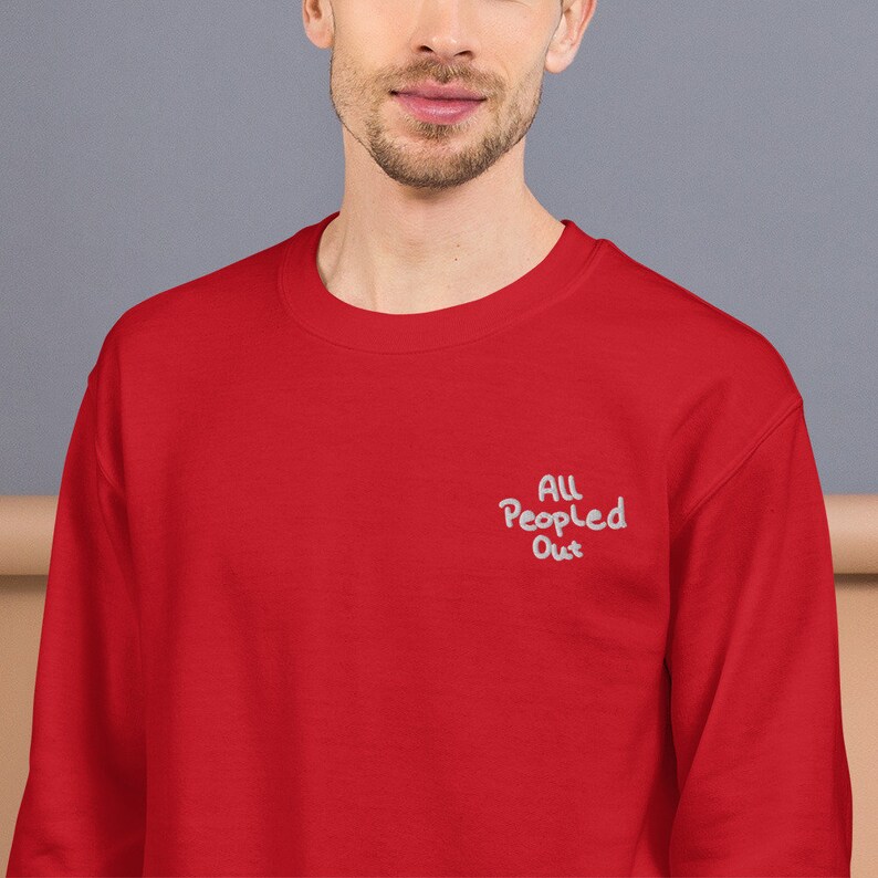 Pode incluir: Camisola de cor vermelha com o texto "All People Out" bordado a branco na frente.