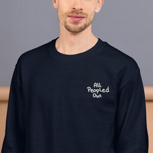 Pode incluir: Uma camisa de moletom azul marinho com o texto "All People Out" bordado em branco na frente.