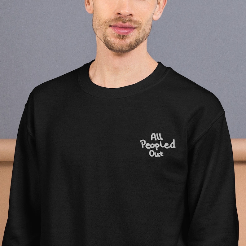 Pode incluir: Camisola de moletom preta com um design bordado branco que diz "All People Out".