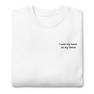 May include: White t-shirt with the text "I wear my heart on my sleeve" printed on the front.