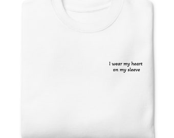 Könnte beinhalten: Weißes T-Shirt mit dem Aufdruck "I wear my heart on my sleeve" auf der Vorderseite.