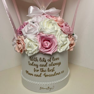Puede incluir: Arreglo floral en una caja redonda blanca, con rosas rosas, blancas y melocot&oacute;n. La caja est&aacute; adornada con perlas y tiene el mensaje: "With lots of love today and always for the best Mum and Grandma xx". Un globo rosa est&aacute; suspendido arriba.