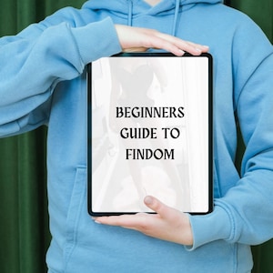 May include: A person holding a tablet with a white background and black text that reads "BEGINNERS GUIDE TO FINDOM".
