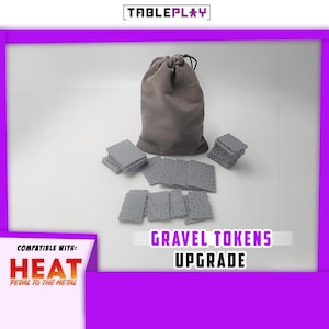 May include: A set of grey gravel tokens and a drawstring bag for board games. The text "GRAVEL TOKENS UPGRADE" is displayed, along with "HEAT PEDAL TO THE METAL". The Tableplay logo is at the top.